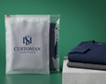 Packaged garment with 'ISH Customan' branding next to folded navy and black clothing on a green background